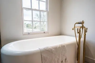 a bath tub in a bathroom with a window at The Limes, Benhall in Saxmundham