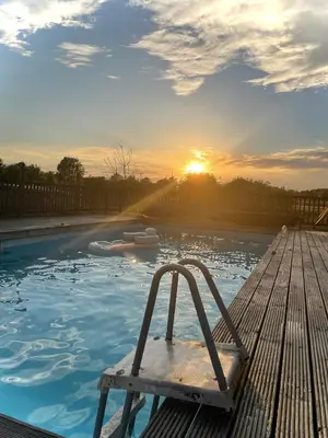a plunge pool with a wooden deck with the sun setting at Spacious Cabin with Private Hot Tub, and Private Pool, in 5 Acres - intimate Special stay For 2 Adults - plus 1 child under 2 and up to 2 dogs stay for free in Downham