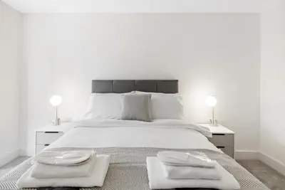 a white bedroom with a large bed with two towels on it at Tailored Stays - Water Street Apartments in Cambridge