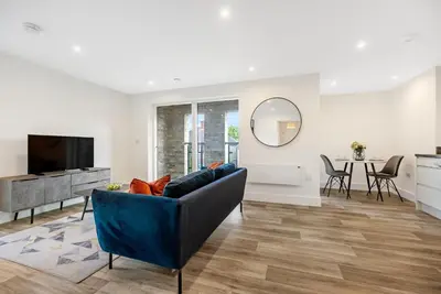 a living room with a blue couch and a television at Tailored Stays - Water Street Apartments in Cambridge