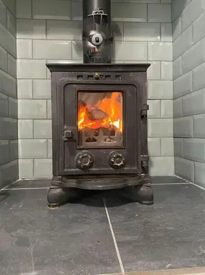 a wood stove with a fire in a room at Lovely 1 bed flat 200 metres from beach in Walton-on-the-Naze