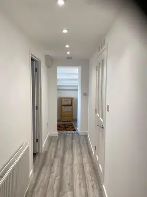 a hallway with white walls and wooden floors and a door at Lovely 1 bed flat 200 metres from beach in Walton-on-the-Naze