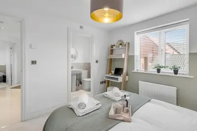 a bedroom with a mirror and a bed with towels at Modern Apartment in Wymondham in Wymondham