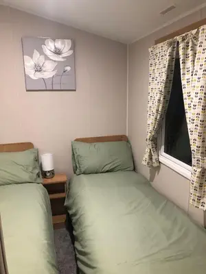 two twin beds in a room with a window at Modern 3 bedroom caravan near the beach in Walton-on-the-Naze