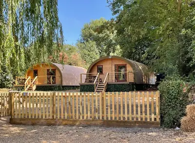 two yurt homes are behind a wooden fence at Cosy and eco-friendly cabins next to 16th century pub in Newmarket