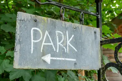 a park sign attached to a metal fence at Cosy and eco-friendly cabins next to 16th century pub in Newmarket