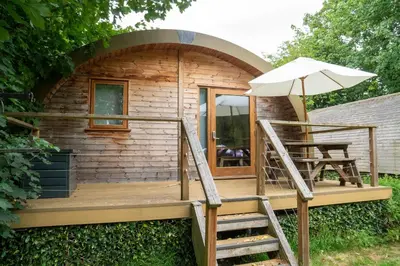a small log cabin with an umbrella and a chair at Cosy and eco-friendly cabins next to 16th century pub in Newmarket