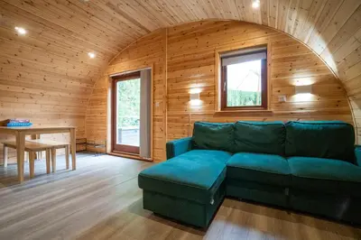 a living room with a blue couch and a table at Cosy and eco-friendly cabins next to 16th century pub in Newmarket