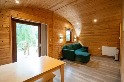 a living room with a green couch and a table at Cosy and eco-friendly cabins next to 16th century pub in Newmarket