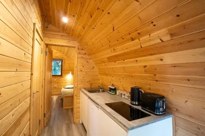 a log cabin kitchen with a counter and a sink at Cosy and eco-friendly cabins next to 16th century pub in Newmarket