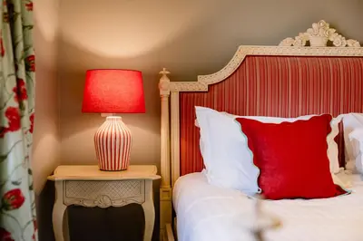 a bedroom with a bed with a red lamp on a table at The Crown, Bildeston in Bildeston