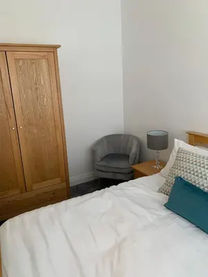 a bedroom with a white bed and a chair at The office at the old Forge in Great Wymondley