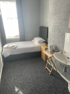 a small room with a bed and a sink at Shakers Inn in Harwich