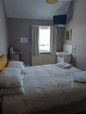 a bedroom with a large white bed and a window at Shakers Inn in Harwich