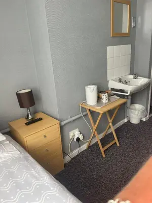 a bedroom with a bed and a sink and a table at Shakers Inn in Harwich