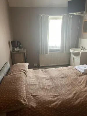 a bedroom with a bed and a sink and a window at Shakers Inn in Harwich