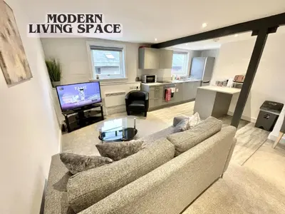 a living room with a couch and a television in it at Fantastic convenient 2 Bedroom 2 bathroom Perfect for Stansted Airport, 3 minute walk to Bishops Stortford Train Station! in Bishops Stortford