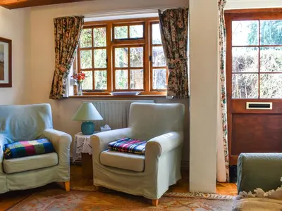 a living room with two chairs and a window at Poppy Cottage in Halesworth