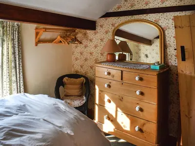 a bedroom with a dresser and a mirror and a bed at Poppy Cottage in Halesworth