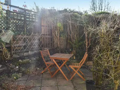 a wooden table and two chairs in a garden at Poppy Cottage in Halesworth