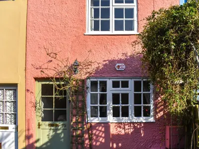 a pink building with a white door and windows at Poppy Cottage in Halesworth