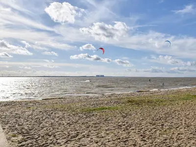 two people are flying kites on the beach at Secretseaview in West Mersea