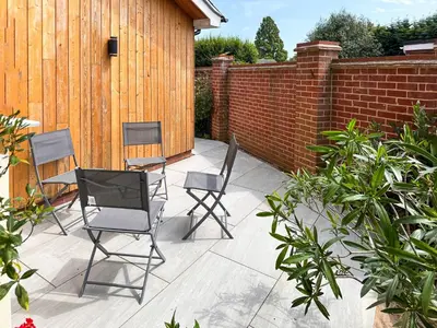 a patio with three chairs and a table and a fence at Secretseaview in West Mersea