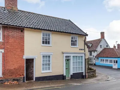 a yellow house with a green door on a street at The Yellow Cottage On The Hill in Framlingham