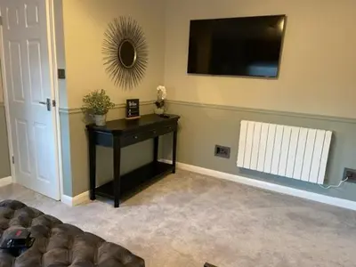 a living room with a table and a television on the wall at Pedlars Rest in Swaffham