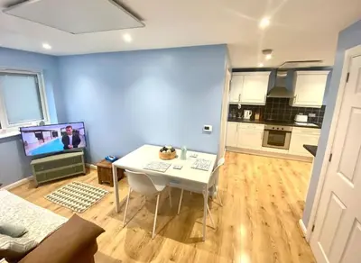 a living room with a white table and a kitchen at Modern Spacious Annex -Ground Floor in Brightlingsea