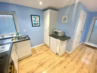 a kitchen with blue walls and a sink and a microwave at Modern Spacious Annex -Ground Floor in Brightlingsea