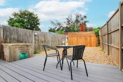 a patio with two chairs and a table on a deck at Mill Dam Lake House in Saint Osyth