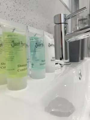 a bathroom sink with three bottles of moisturizers on it at Cambridge Studios and Suites by Tas Accommodations in Cambridge
