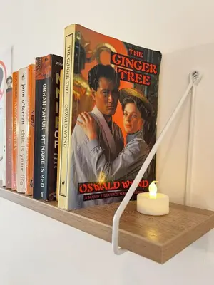 a book shelf with books and a candle on it at Cambridge Studios and Suites by Tas Accommodations in Cambridge