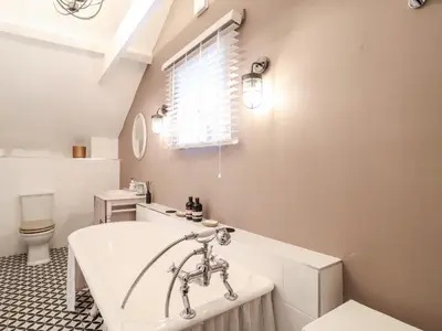 a bathroom with a tub and a toilet and a sink at Tower End Cottage in Woodbridge