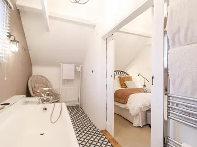 a bathroom with a tub and a bed in a room at Tower End Cottage in Woodbridge