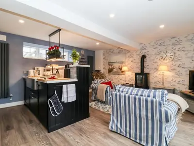 a living room with two couches and a kitchen at Tower End Cottage in Woodbridge