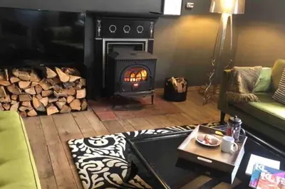 a living room with a fireplace and a green couch at The Old Mill, 7 storey,, dog friendly outdoor pool & bbq in Stoke Ferry
