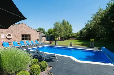 a swimming pool with blue chairs and a house at The Old Mill, 7 storey,, dog friendly outdoor pool & bbq in Stoke Ferry