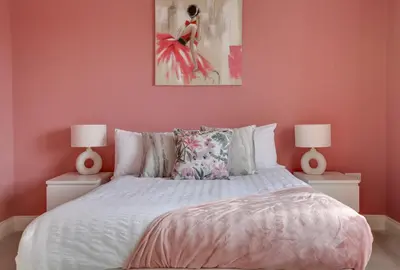 a bedroom with pink walls and a bed with two lamps at Elizabeth Townhouse Braintree in Bocking Churchstreet