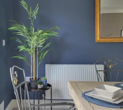 a dining room with a table with a plant on a blue wall at Elizabeth Townhouse Braintree in Bocking Churchstreet