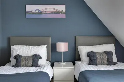 a bedroom with two beds and a blue wall at Elizabeth Townhouse Braintree in Bocking Churchstreet