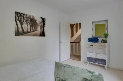 a bedroom with a dresser and a painting on the wall at Elizabeth Townhouse Braintree in Bocking Churchstreet
