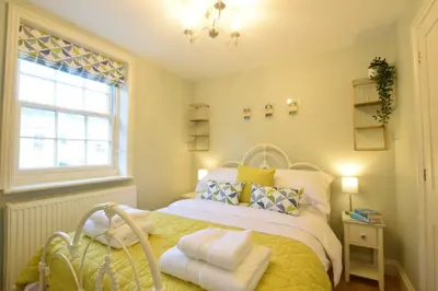 a bedroom with a bed with a yellow blanket and a window at 11 Crabbe Street, Aldeburgh in Aldeburgh