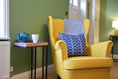 a yellow chair with a blue pillow on a side table at 11 Crabbe Street, Aldeburgh in Aldeburgh