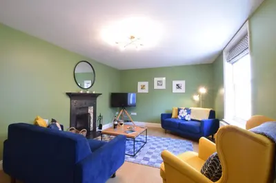 a living room with two blue couches and a fireplace at 11 Crabbe Street, Aldeburgh in Aldeburgh