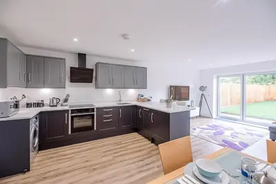 a kitchen with black cabinets and a large window at 4 Eureka Waldringfield in Woodbridge