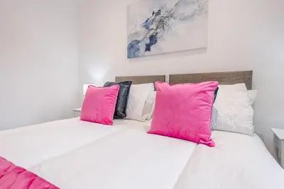 a white bed with pink pillows on top of it at 4 Eureka Waldringfield in Woodbridge