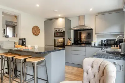 a kitchen with white cabinets and a island with bar stools at 3 Bed in Aldeburgh oc-16afaw in Aldeburgh