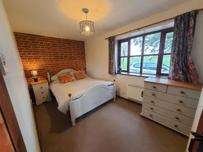 a bedroom with a bed and a brick wall at Cosy Rural Barn Conversion 5 Min Drive To Pin Mill 1 BR + sofa bed in Chelmondiston
